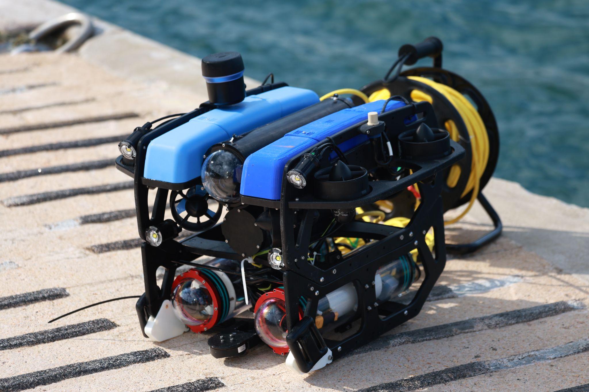 Our blue underwater ROV with its integrated sensing payload and tether reel beside the water